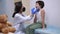 Side view female pediatrician checking little patient sore throat with disposable spatula. Caucasian woman in
