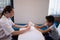 Side view of female therapist wrapping bandage on hand while boy sitting at table