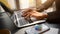 Side view of female working on laptop while looking business chart on smartphone