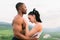 Side view of fit mixed race couple with perfect bodies in sportswear softly embracing on mountains landscape