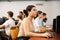 Side view on focused teenager female student sitting at desk in computer class, preparing for exam