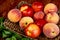 side view of fresh ripe nectarines and peaches on a wicker tray on wooden rustic background