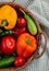 side view of fresh vegetables ripe tomatoes colorful bell peppers green chili peppers and cucumbers in a wicker basket on plaid