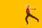 Side view full-length portrait of bouncing boy on yellow background. Child jumps happily. Copy space, place for text