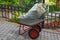 Side view on garden wheelbarrow with red wheels and to big white bags with foliage