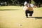 Side view of golfer crouching and looking his ball