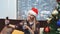 Side view of good-looking woman making selfie in Santa hat and with drink in her hands