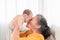 Side view grandmother and newborn baby play together at home, Grandma holding adorable infant in air and kissing with love and