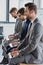 side view of handsome young businessmen in suits sitting and using laptops