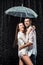side view of happy couple in white shirts standing under umbrella under raindrops