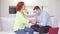 Side view of happy loving Caucasian adult couple sitting on couch looking at each other and man kissing woman hands