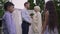 Side view of happy Middle Eastern woman and Caucasian man talking on wedding day with blurred children chatting at front