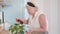 Side view of happy senior woman spraying water on green plant at home. Middle shot portrait of relaxed Caucasian retiree