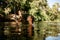 side view of head of wet woman with wakeboard standing in deep river water.