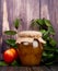 side view of honey in a glass jar and fresh ripe nectarine with green leaves on rustic wooden background