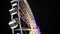 Side view of huge Ferris wheel rotating at amusement park under dark night sky