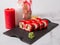Side view of Japanese sushi roll with salmon, avocado, cucumber and flying fish roe on top. rose petals and candles near served