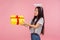 Side view of joyful asian angelic girl with long brunette hair and nimbus over head holding gift box