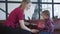 Side view of joyful woman and little girl shaking pink gift box. Portrait of blond Caucasian mother and daughter opening