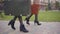 Side view of legs in high heels of two women holding old travel bags and walking. Elegant female friends travelling