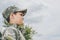 side view of little boy in camouflage clothing with cloudy sky