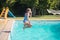 Side view of little Caucasian girl jumping into pool