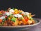 Side view of loaded minced pork nachos on plate with black wall background