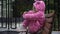 Side view lonely sad girl in pink costume sitting on bench outdoors thinking. Portrait of Caucasian child alone on city