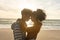 Side view of loving biracial couple romancing while standing face to face at beach during sunset