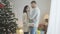 Side view of loving couple standing at home at Christmas tree face to face. Happy Caucasian man and woman enjoying New