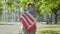 Side view of loving international students hugging on sunny university yard. Portrait of positive American man and