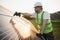 Side view of male worker installing solar modules and support structures of photovoltaic solar array.