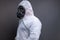 Side view of man with gas mask in protective overall suit against grey background