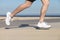 Side view of a man legs running on the concrete of a seafront