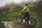 Side view of a man on a mountain bike standing on a rocky terrain and looking at a rock. The concept of a mountain bike