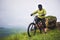 Side view of a man on a mountain bike standing on a rocky terrain and looking at a rock. The concept of a mountain bike