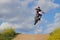 Side view of man performing stunt with motorcycle on motocross track