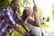 Side View Of Man Pushing Woman On Tire Swing In Garden