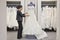 Side view of a mature employee adjusting elegant wedding dress in bridal store