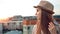 Side view melancholic woman in hat enjoying city landscape at amazing sunset on roof or balcony