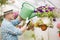 Side view of middle-aged man watering flower plants in greenhouse