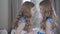 Side view middle shot of angry little Caucasian girl scolding her twin sister. Pretty siblings in blue dotted dresses