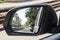 Side view mirror in modern car with view of street with parked c