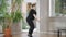 Side view of motivated overweight sportswoman doing jump squats indoors. Wide shot of confident Caucasian young woman