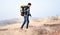 Side view moving wide angle shot of traveller with backpack hiking the mountain by holding stick during winter - concept of solo