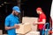 side view of multicultural delivery men in red and blue uniform with cardboard