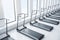 Side view of new grey treadmills in modern gym interior with windows, daylight and concrete floor. Fitness club concept. 3D