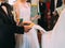 The side view of the newlyweds holding candles with green ribbons and the ceremonial embroidered towel.