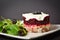 Side view of Norwegian layered fish salad Herring under fur coat. Portion with marinated herring, onion, grated potato, beetroot,