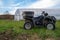 Side view of off road farm vehicle in green grass with greenhouse